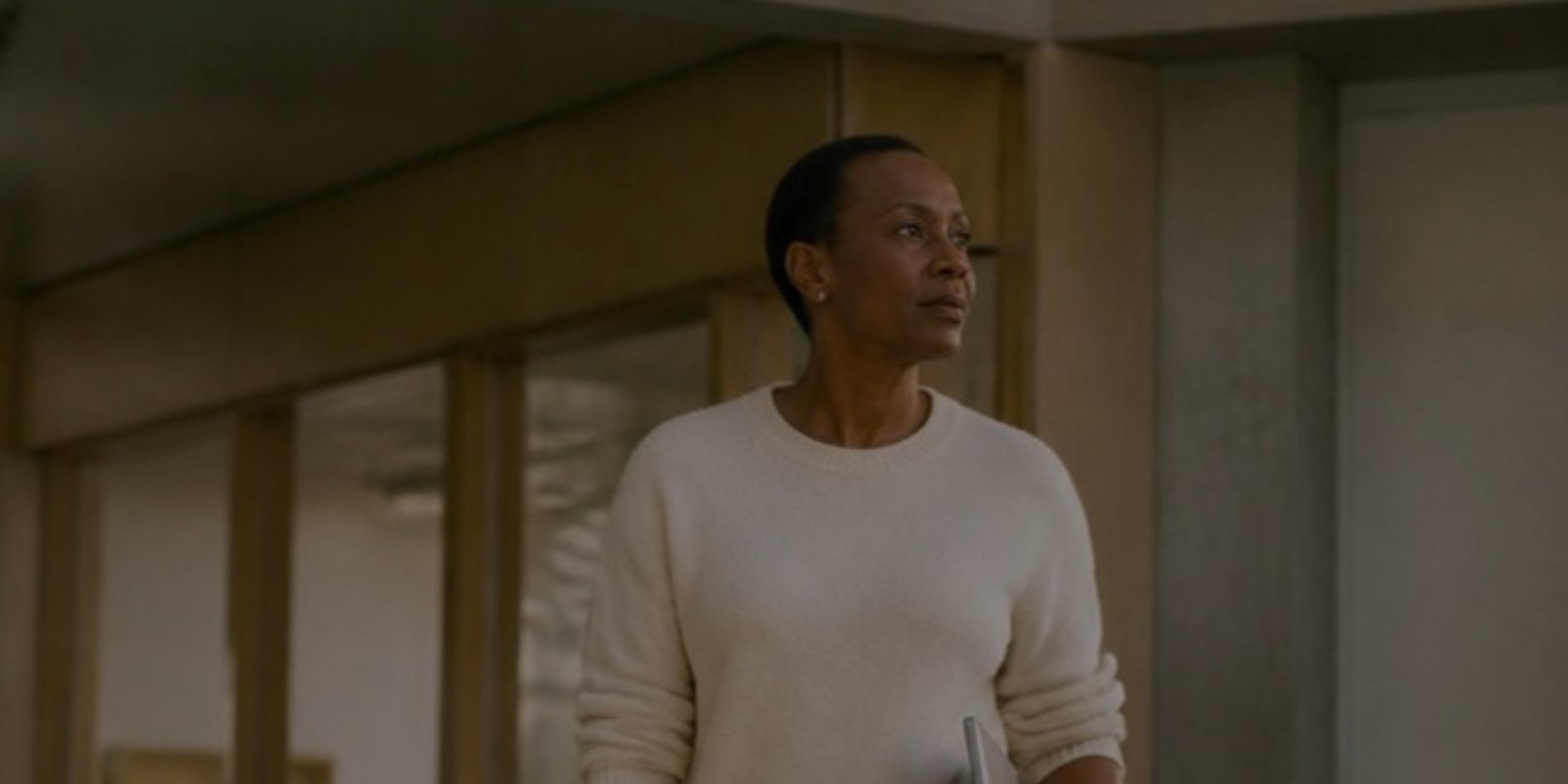 Woman in a cream sweater standing in an office hallway