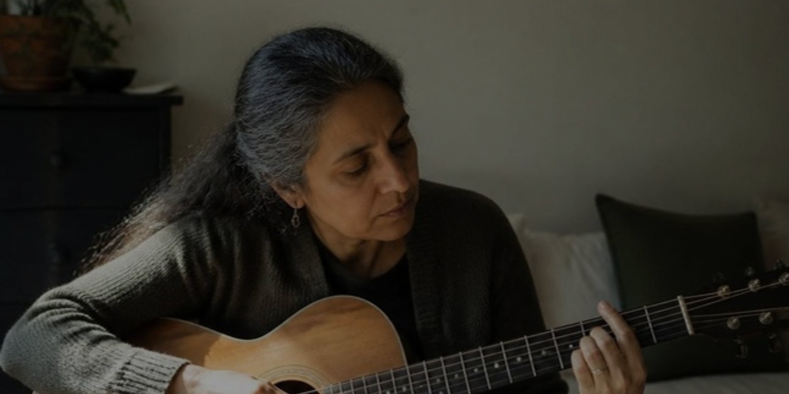 Woman playing an acoustic guitar at home
