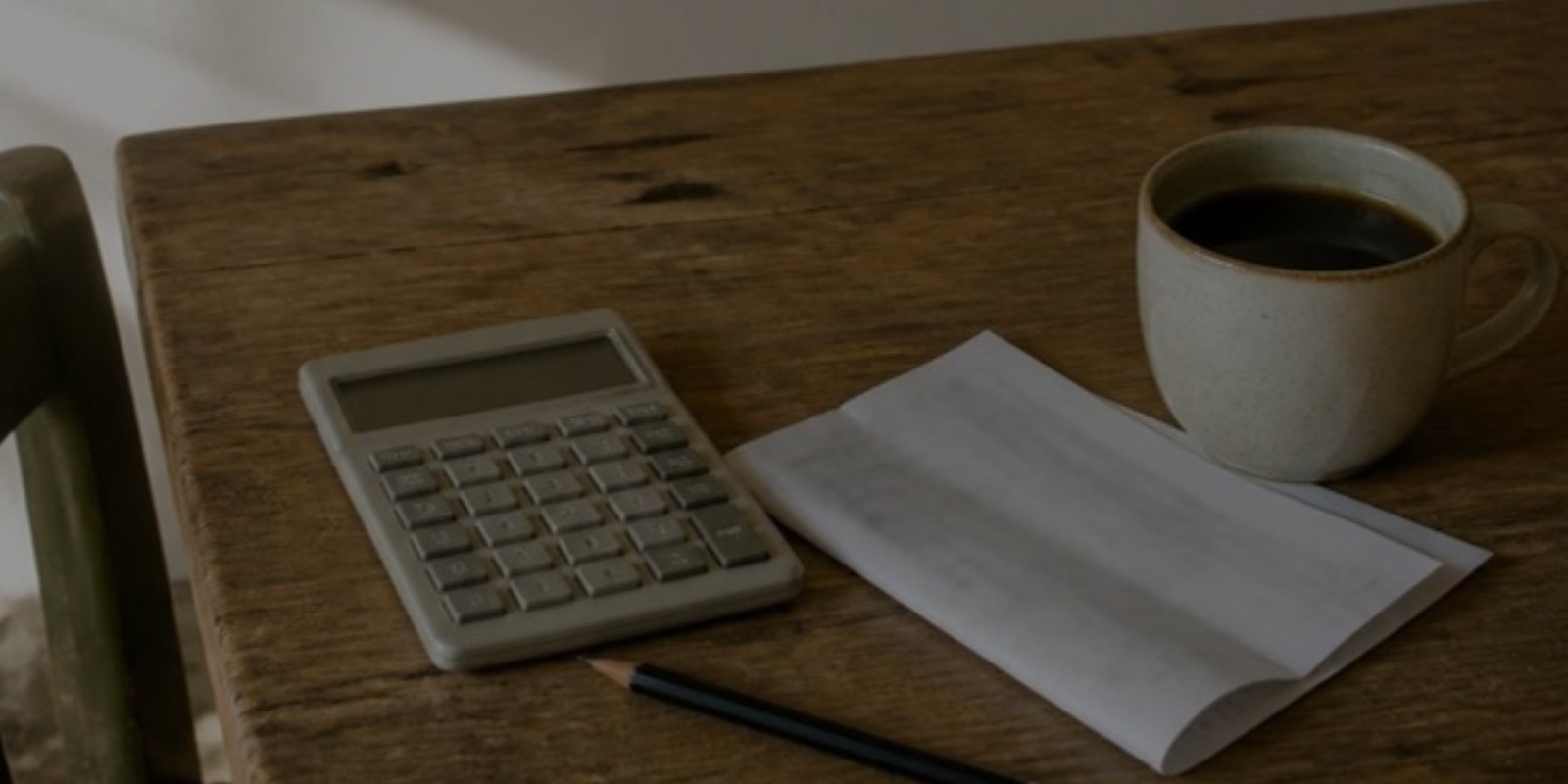 ms-why-good-salary-still-feel-broke-v2 Calculator, pay stub, pencil and cup of coffee on a wooden table